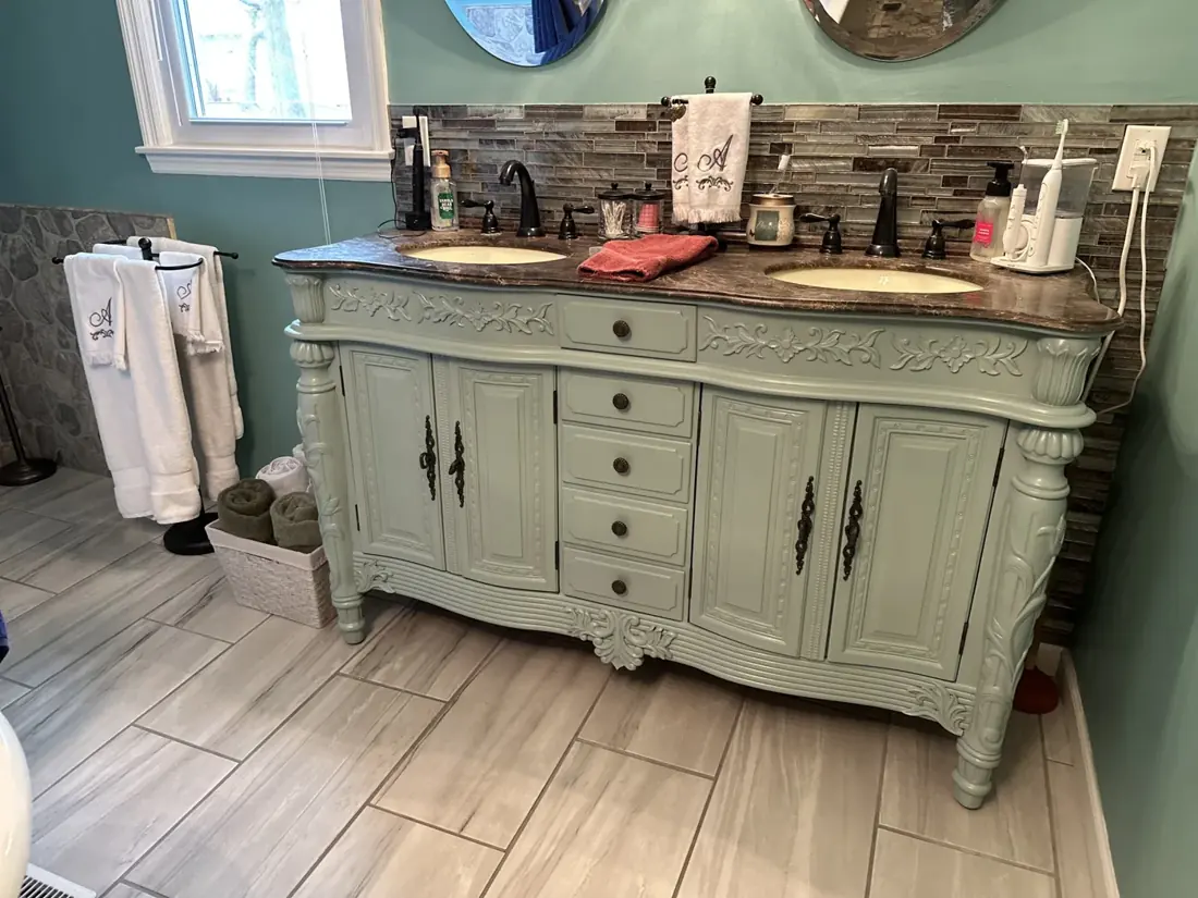 Bathroom vanity painted soft green with its decorative details preserved